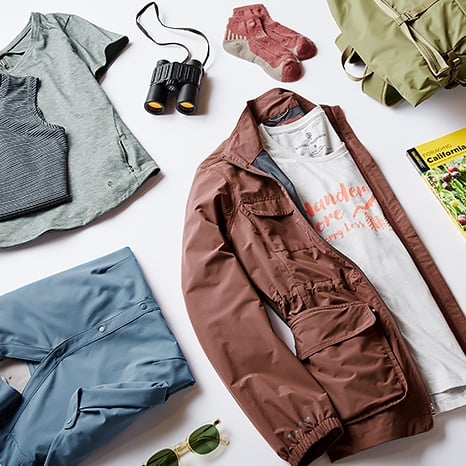 Various hiking clothes and gear laid flat on a white background. 